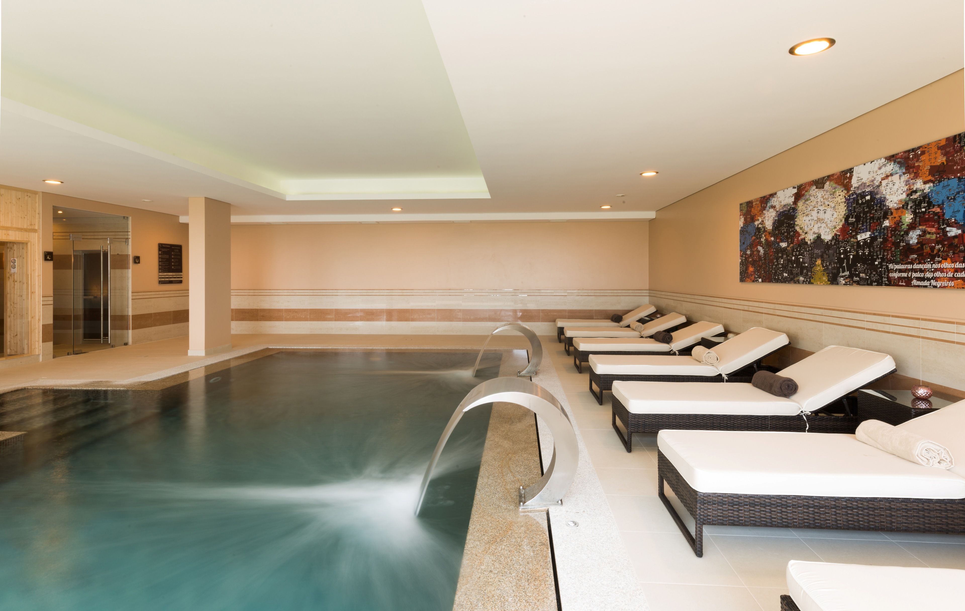 A swimming pool with lounge chairs and a glass door entrance.