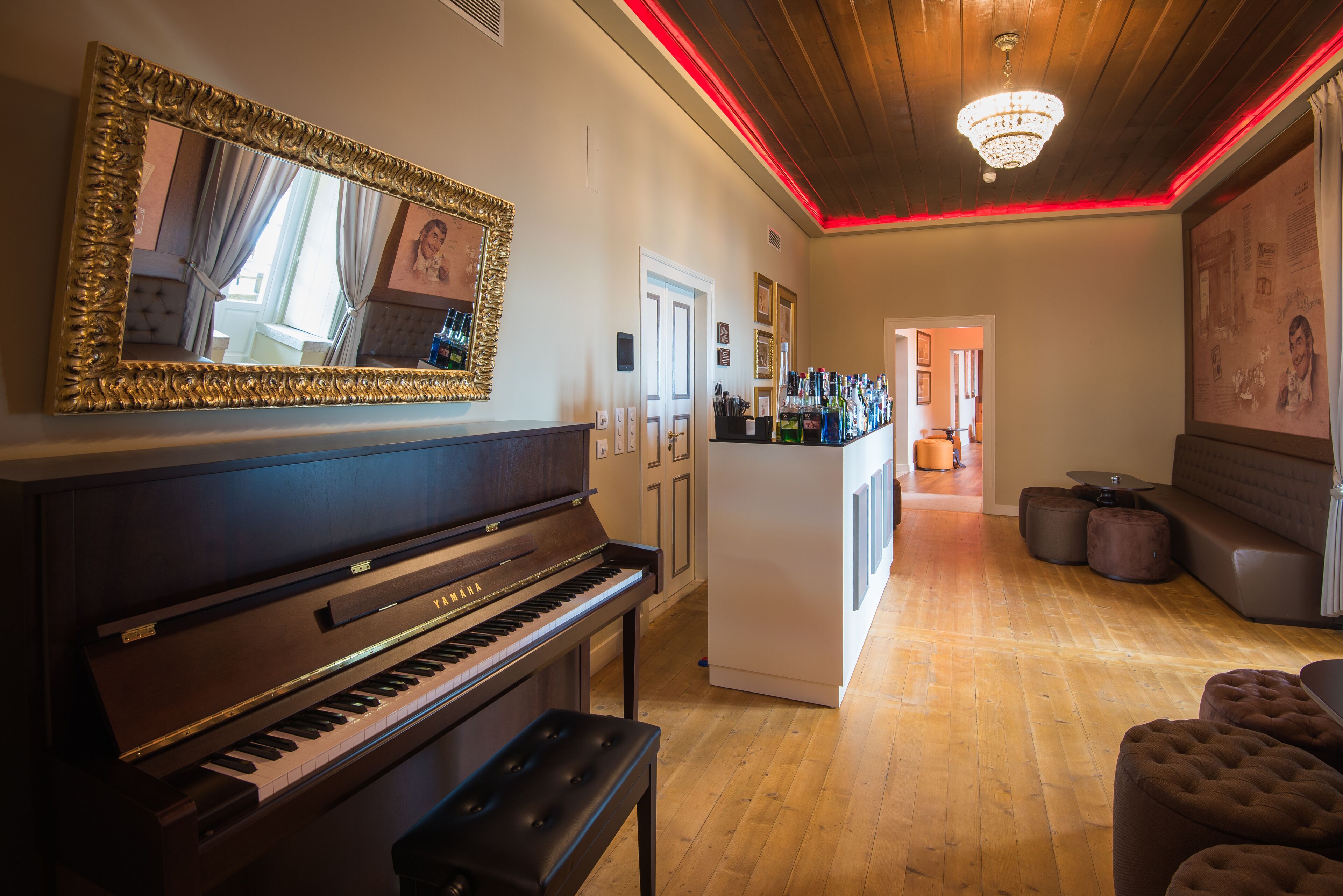 A living room with a grand piano, a white refrigerator, and a bar area with stools.