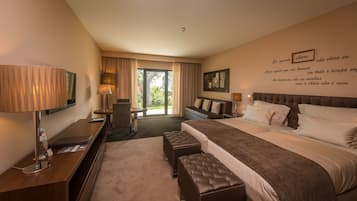 Ein Hotelzimmer mit Bett, Nachttischen, Schreibtisch, Stuhl, Lampe und Blick ins Freie.