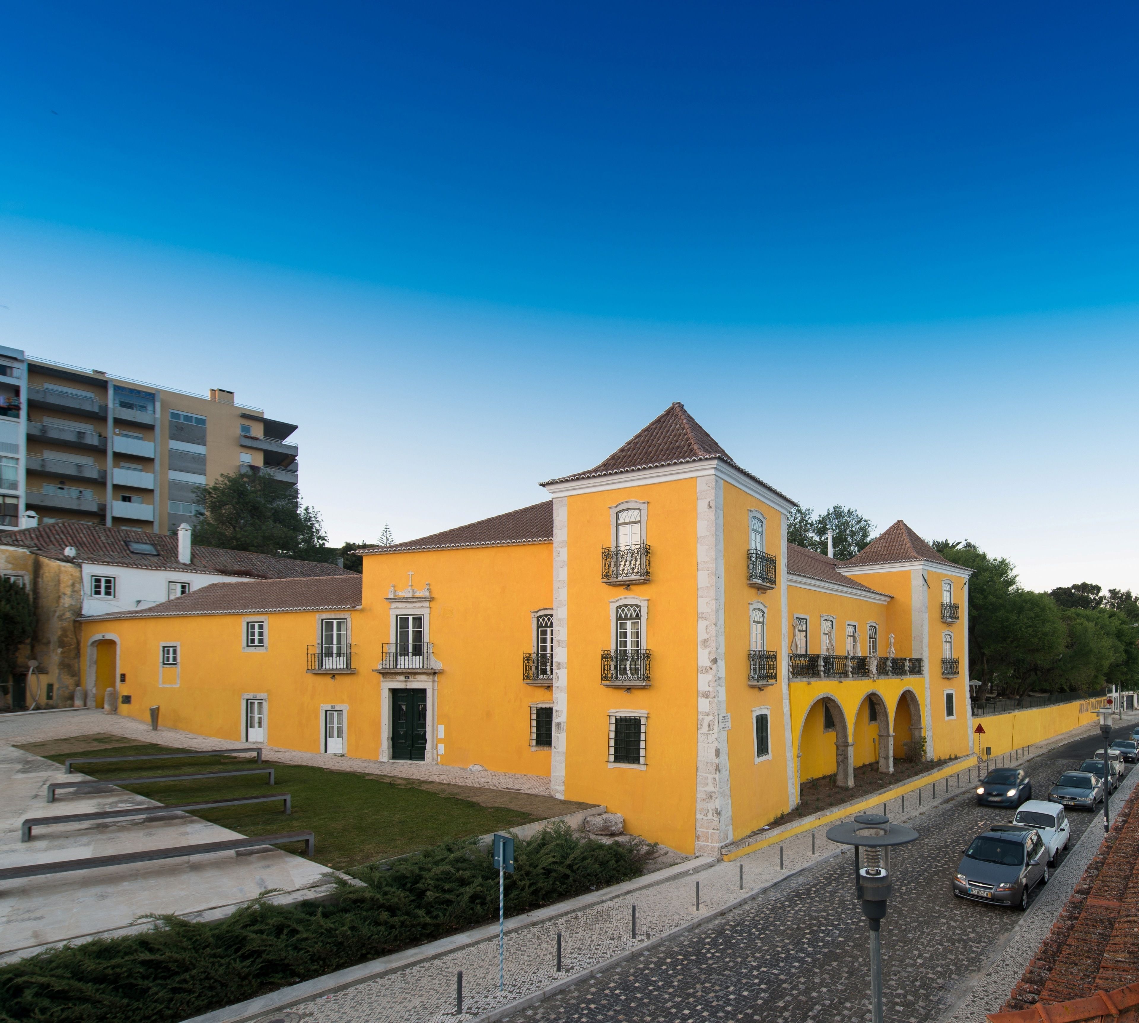 Un edificio amarillo con una torre central, múltiples ventanas y balcones.
