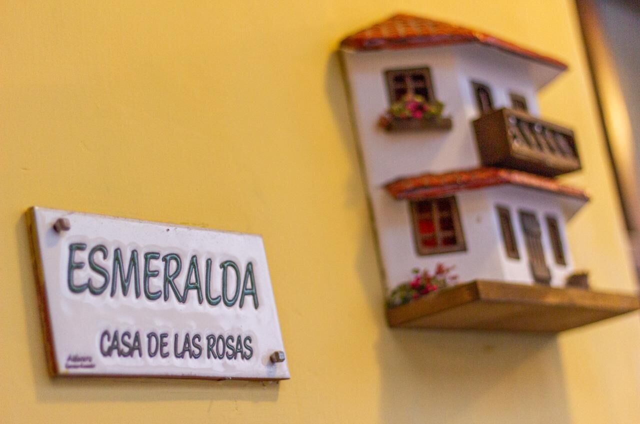 A sign reading "ESMERALDA CASA DE LAS ROSAS" mounted on a wall.