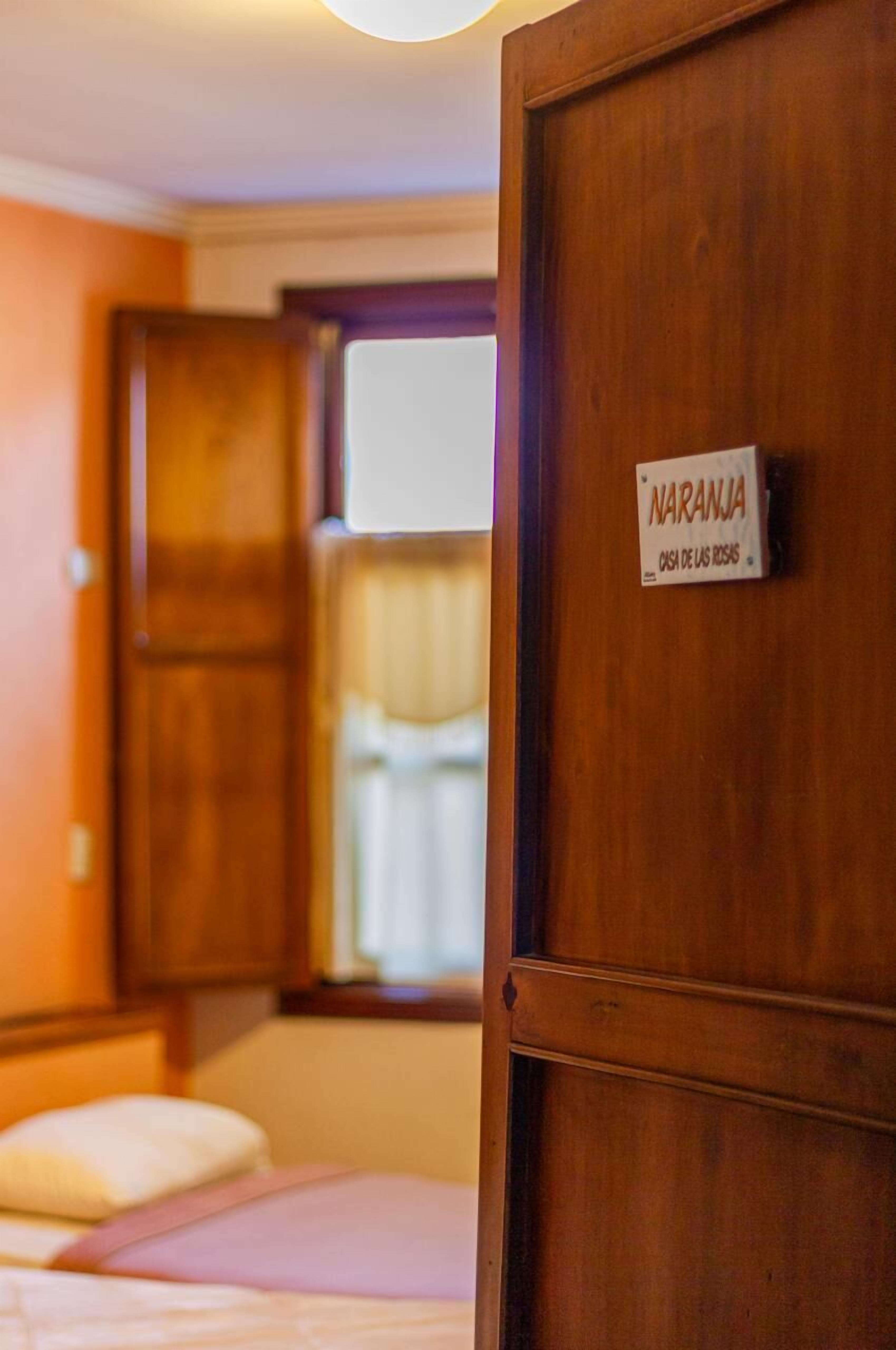 Eine Holztür mit einem Schild, auf dem "NARANJA" und "OSA DE LAS RISAS" steht.