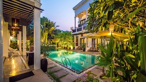 Una piscina al aire libre, sombrillas, sillones reclinables de piscina