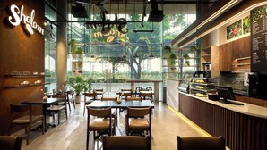 A modern cafe interior with tables, chairs, a coffee bar, and a menu board.