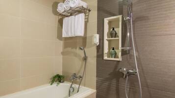 A bathroom with a bathtub, a shower, and a towel rack with folded towels.