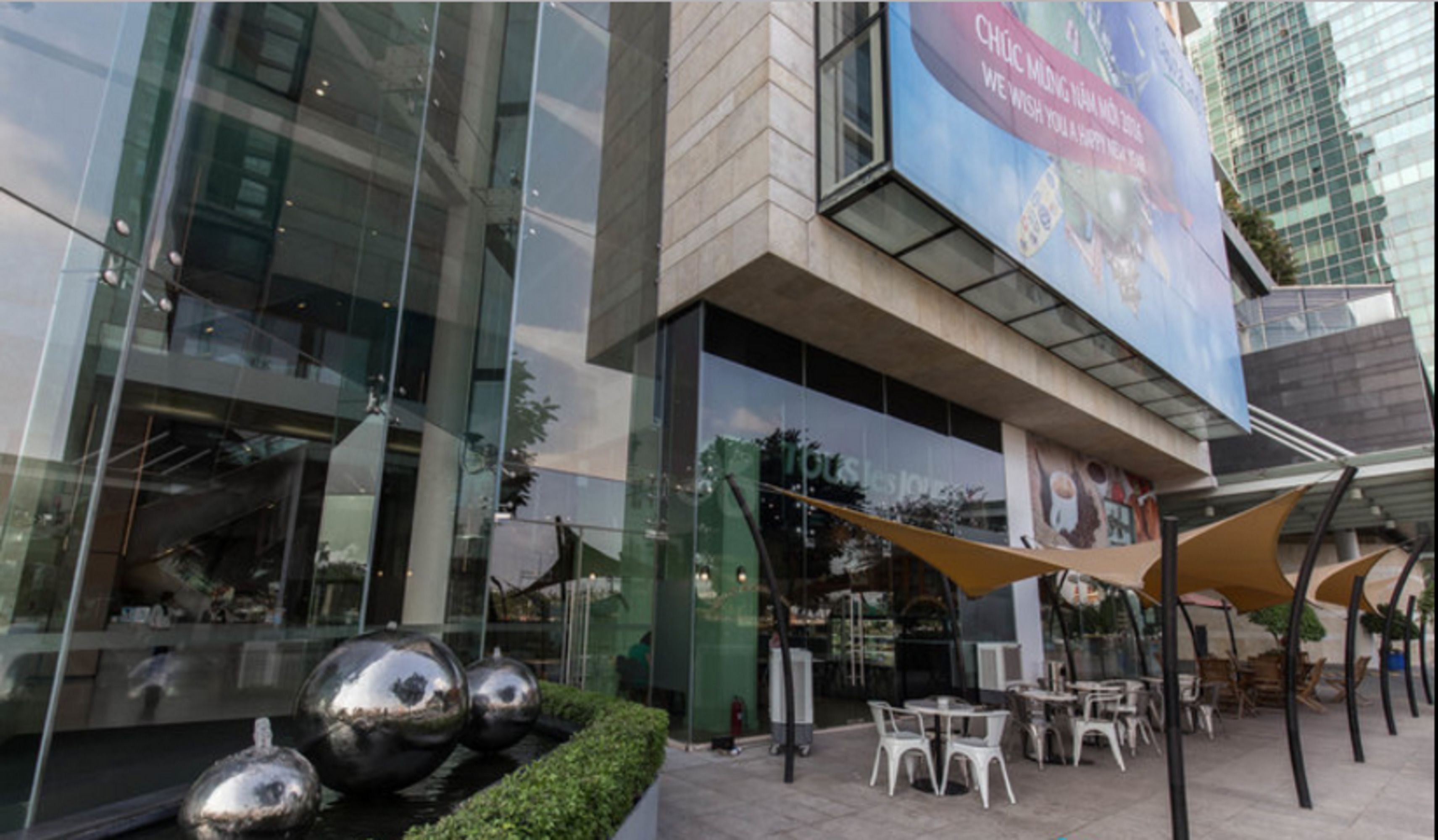 A modern building with large glass windows, outdoor seating, and a water feature.