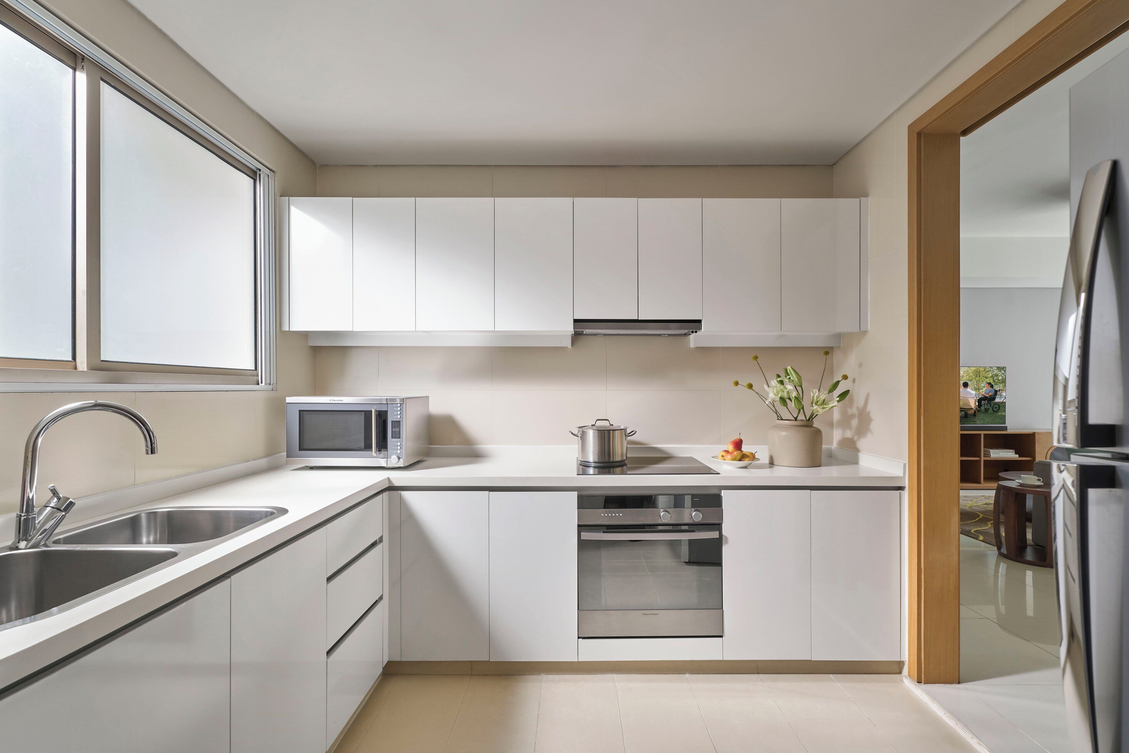 A modern kitchen with white cabinets, stainless steel appliances, and a window providing natural light.