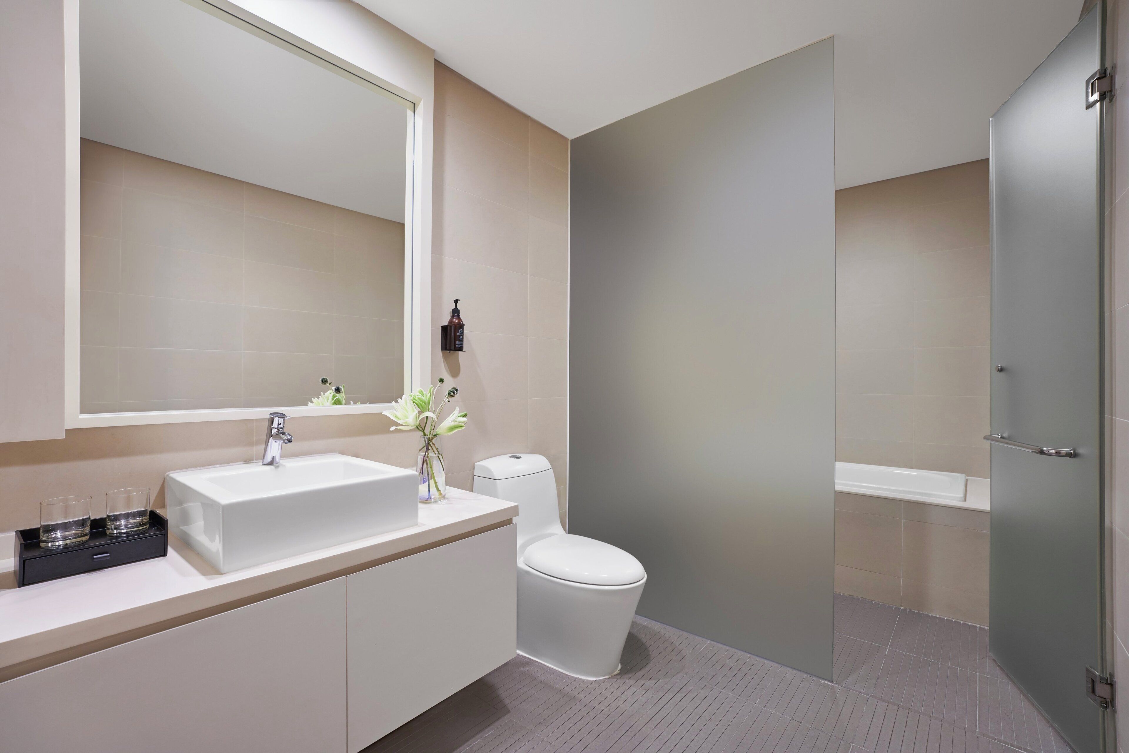 A modern bathroom with a large mirror, white sink, and a toilet.