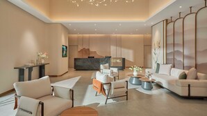 A modern hotel lobby with a reception desk, seating area, and decorative elements.
