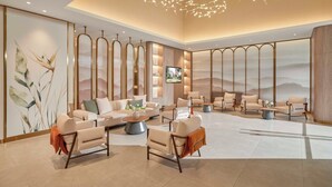 A spacious lobby with modern furniture, a large flat-screen TV, and decorative lighting.