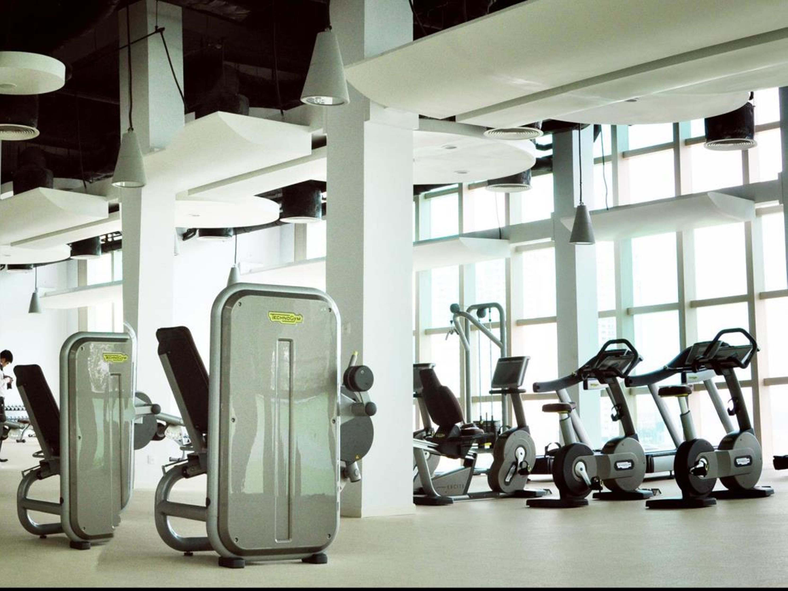 A gym with cardio machines, weight machines, and a treadmill.