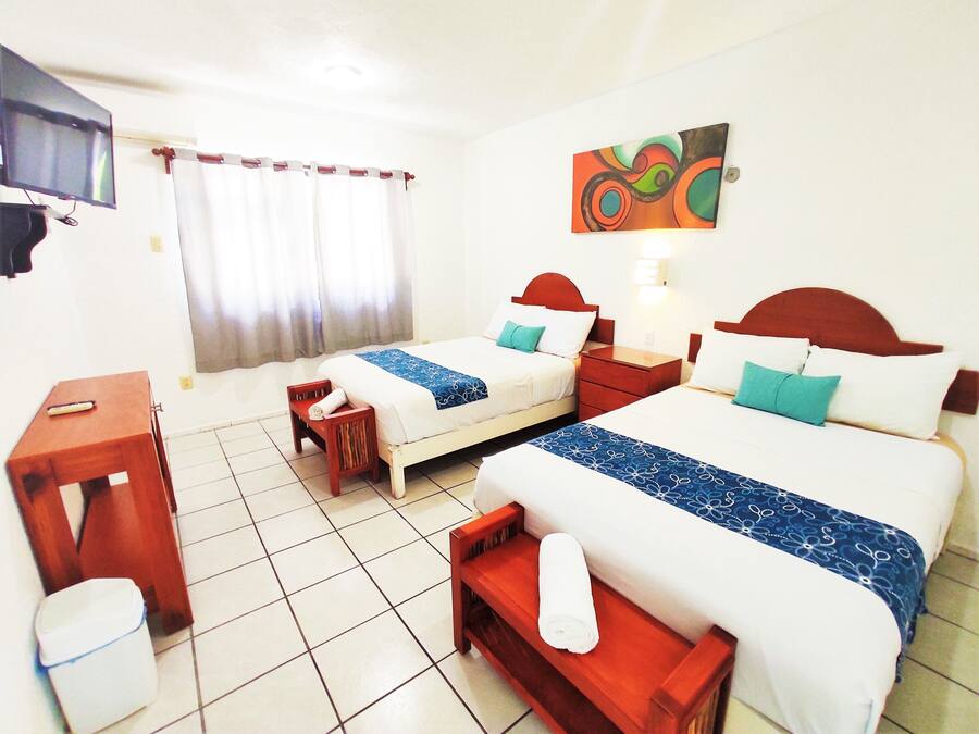 A hotel room with two beds, a TV, a desk, and a bathroom.