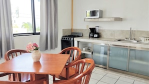 A kitchen with a dining table and chairs, a stove, a microwave, a blender, and a sink. - Fragata Departamentos (Puerto Morelos)