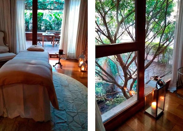 A bedroom with a bed, a small table, and a view of a garden through a window. - Hub Porteño (Buenos Aires)