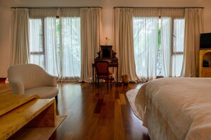 A hotel room with a bed, a wooden desk with a chair, a bench, and a TV on a wooden stand. - Hub Porteño (Buenos Aires)