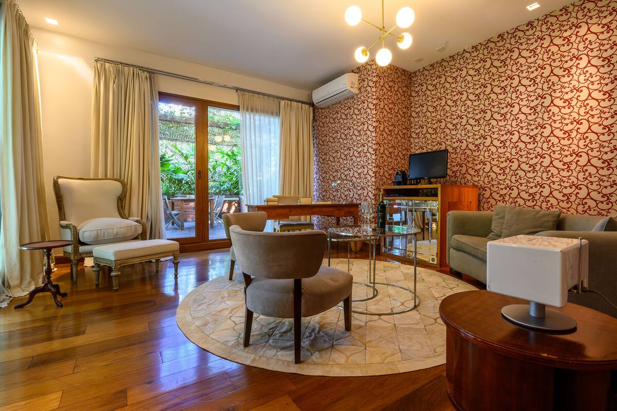 A living room with a wooden floor, a round coffee table, a sofa, a chair, and a television on a stand.