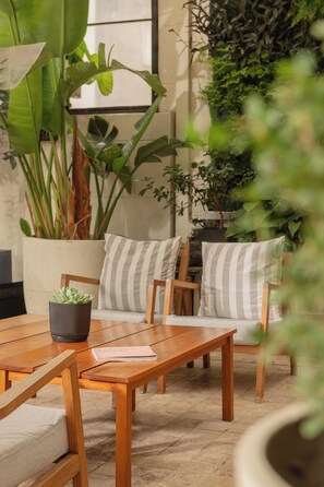 A wooden table with a potted plant and a book on it, a striped cushion, and a chair with a similar cushion. - Hub Porteño (Buenos Aires)