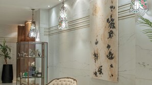 Una habitación amplia con dos sillones tapizados, un aparador de cristal y un gran elemento decorativo en la pared.