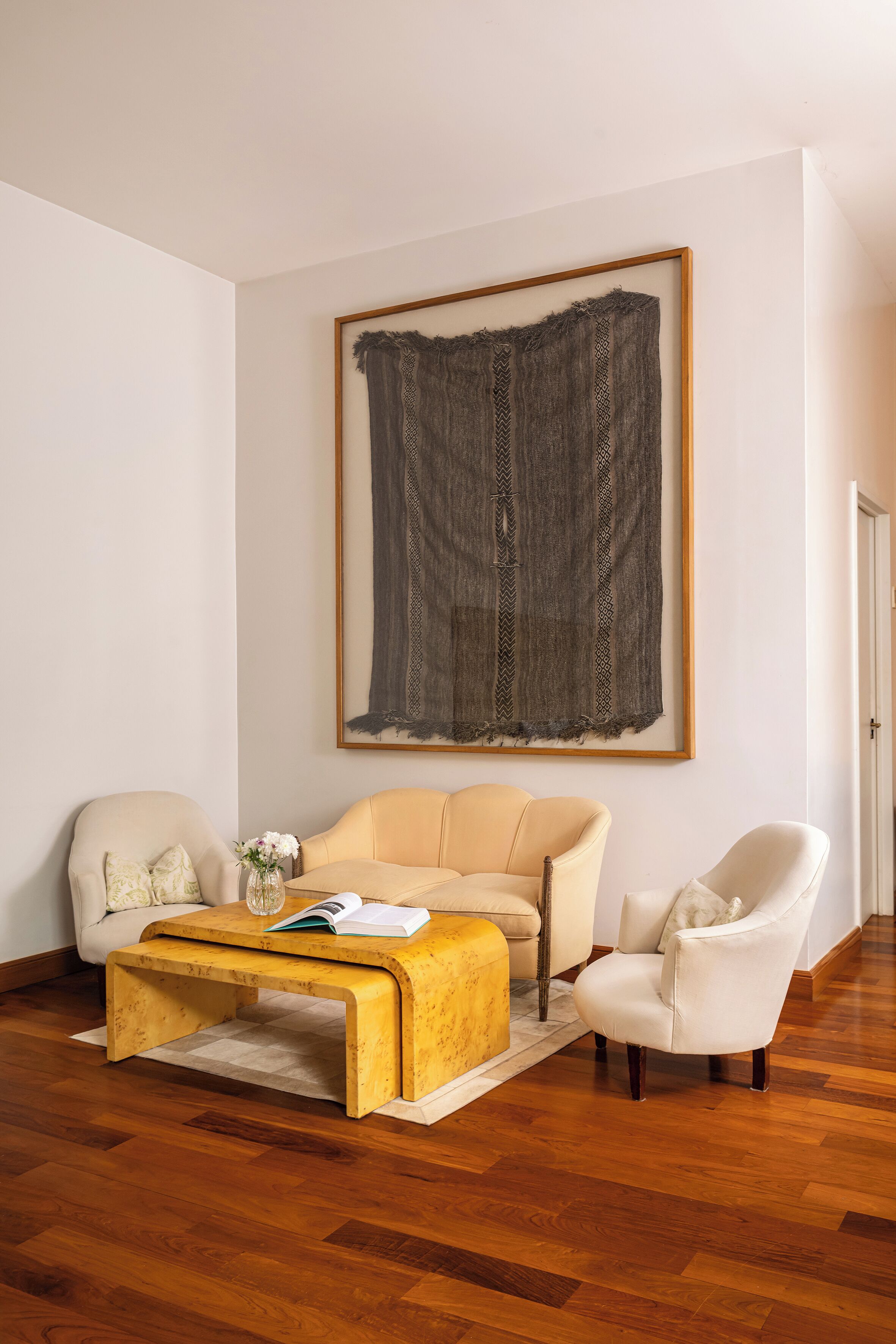 A living room with a sofa, armchairs, a coffee table, and a large abstract painting on the wall.