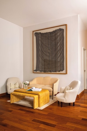 Un salon comprenant un canapé, des fauteuils, une table basse et un grand tableau abstrait accroché au mur.