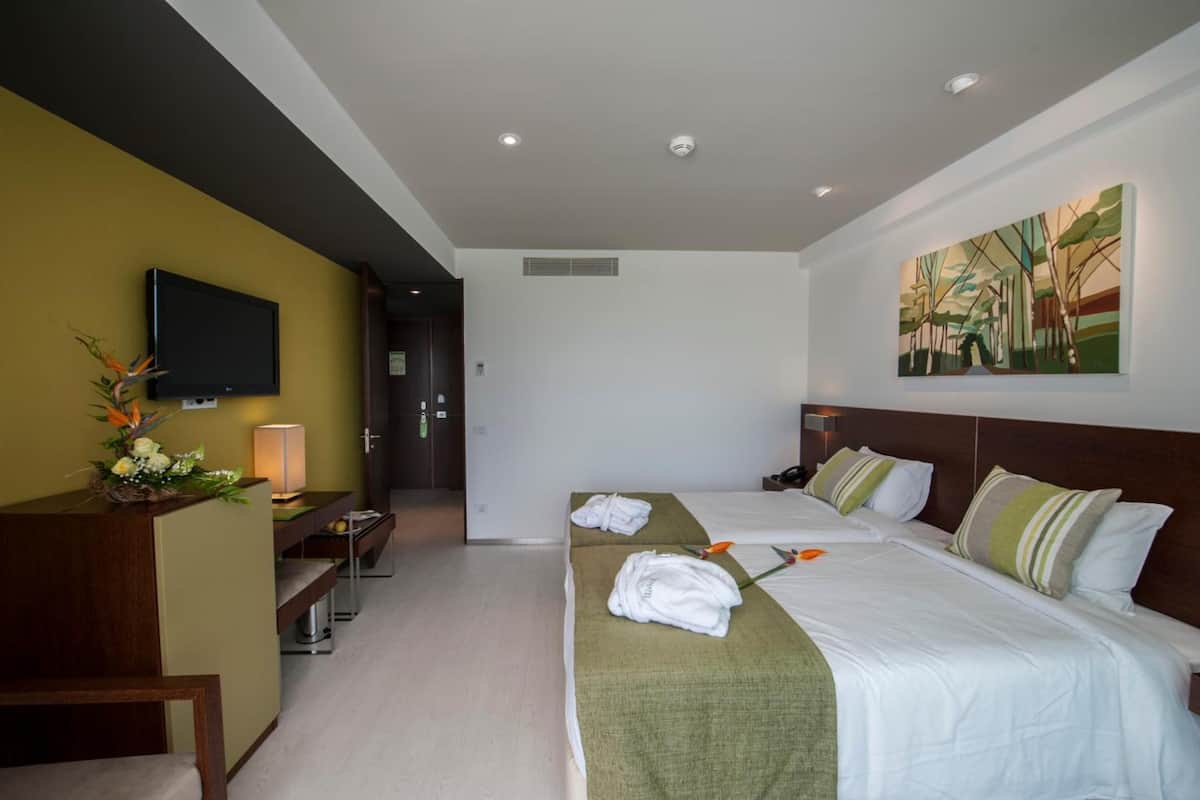 Une chambre d’hôtel avec deux lits, un bureau, une télévision et un tableau au mur.