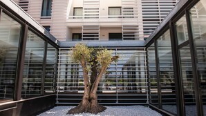 A modern building with large glass windows and a central tree in a gravel area. - INATEL Cerveira Hotel (Vila Nova de Cerveira)
