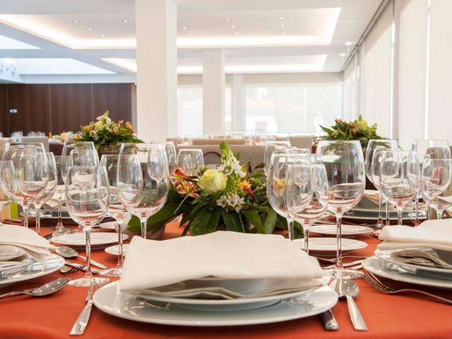 A dining table set with multiple wine glasses, plates, and cutlery, with floral centerpieces.