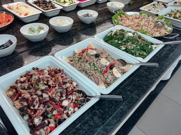 A buffet with various dishes including salads, meats, and vegetables.