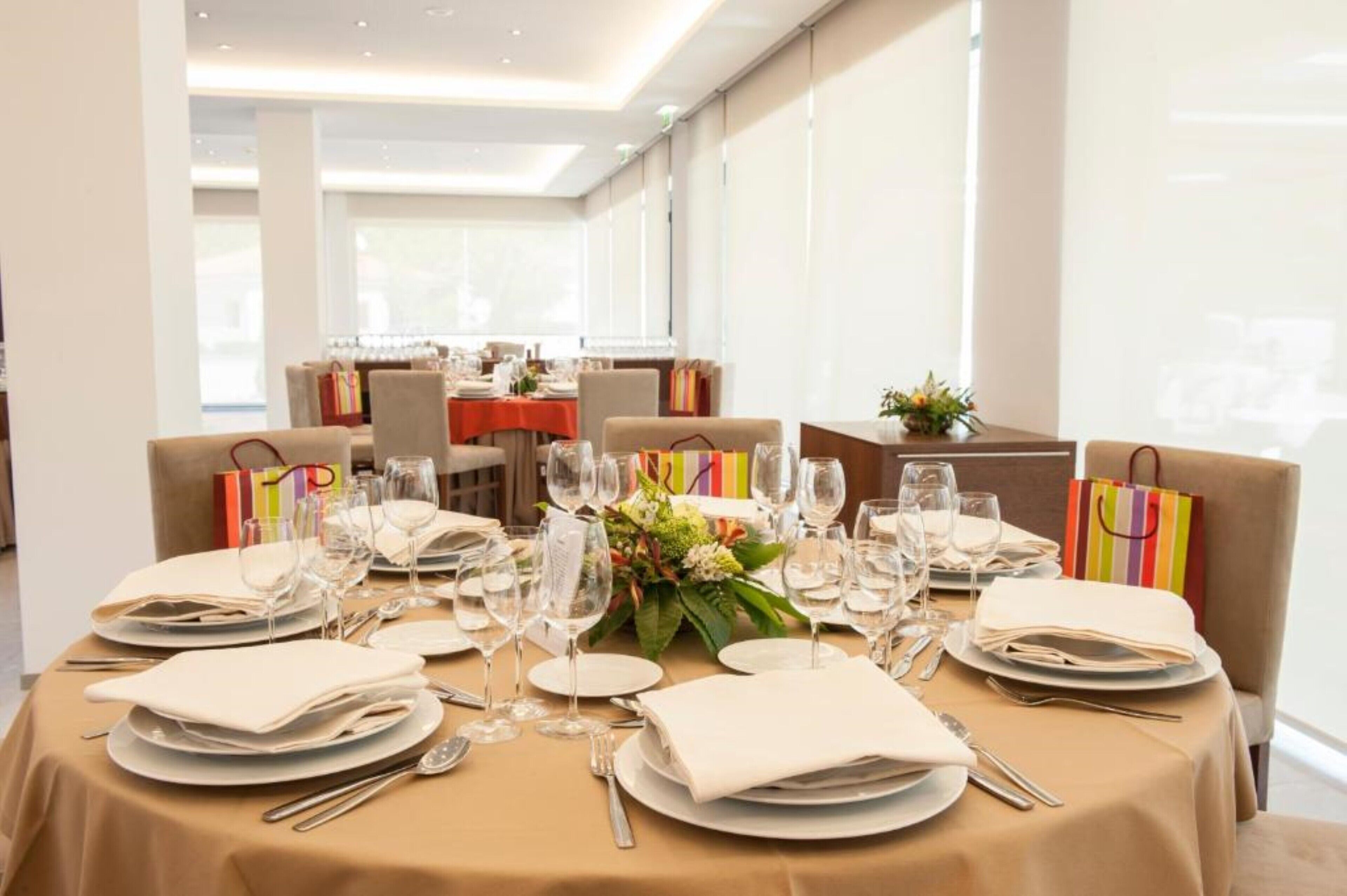 A dining area with tables set for a meal, featuring neatly arranged plates, glasses, and cutlery.