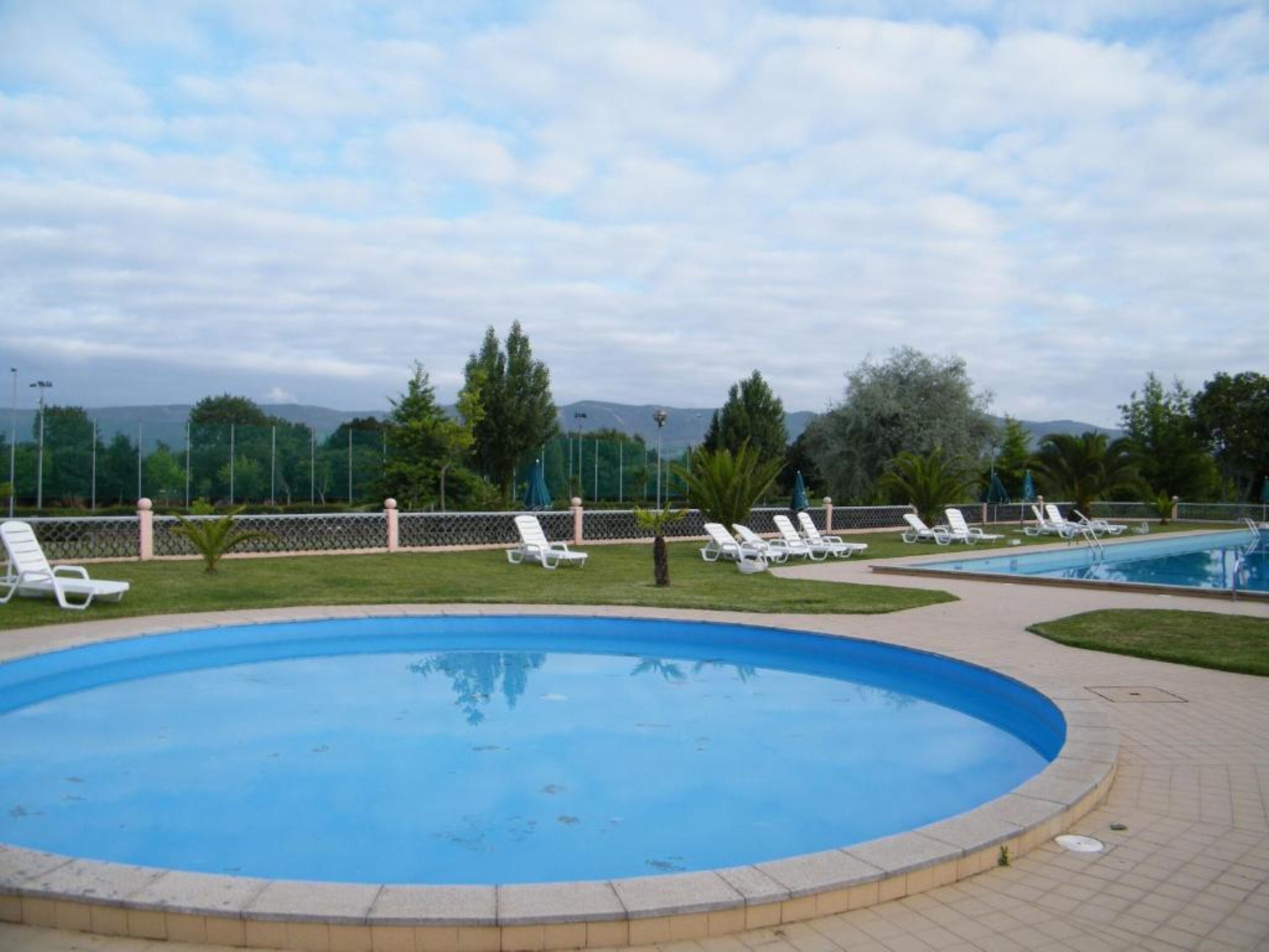 Una piscina con sillones de descanso y vistas a montañas al fondo.