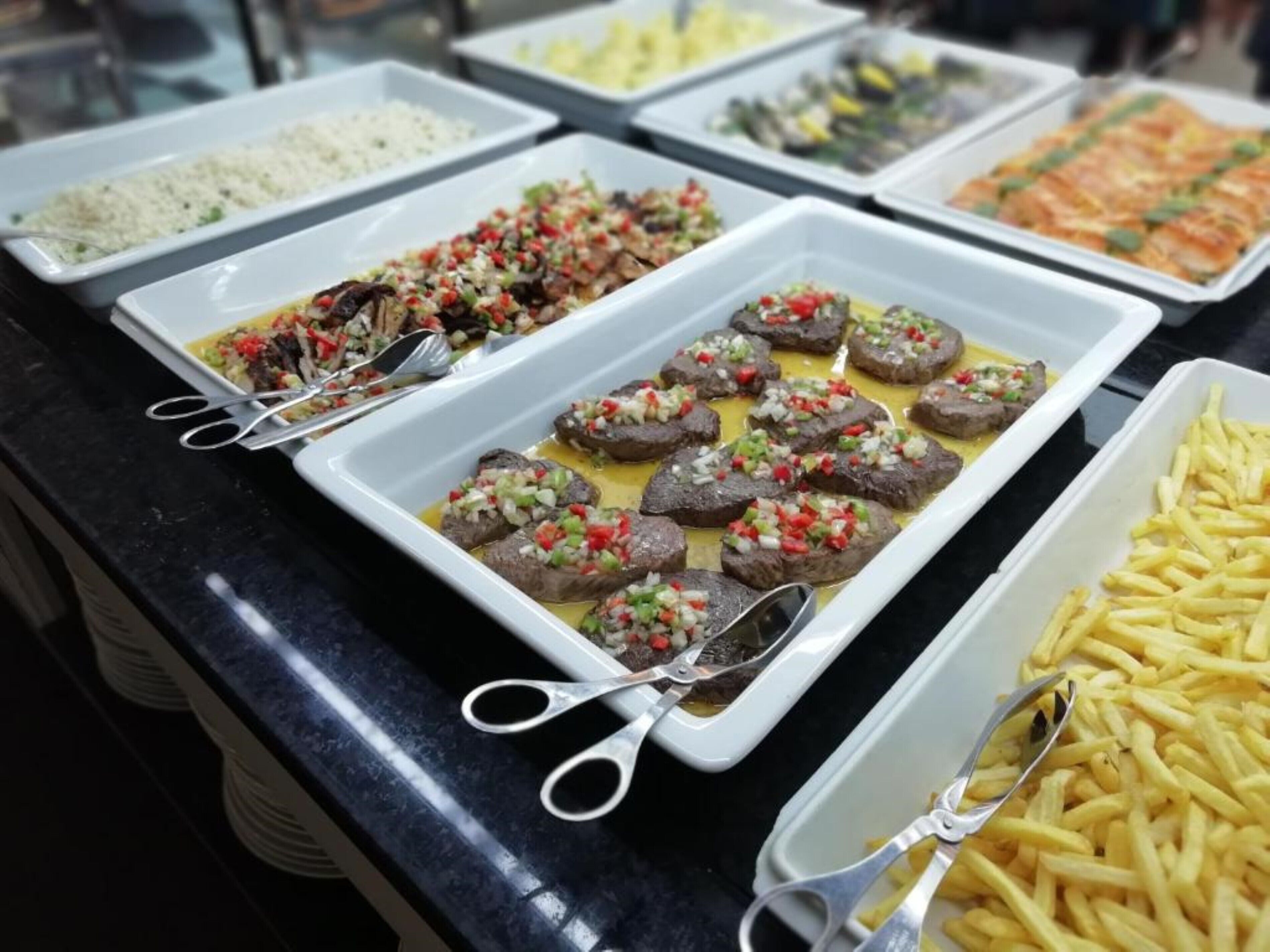 Un bufé con diversos platos, incluyendo albóndigas, arroz y papas fritas.
