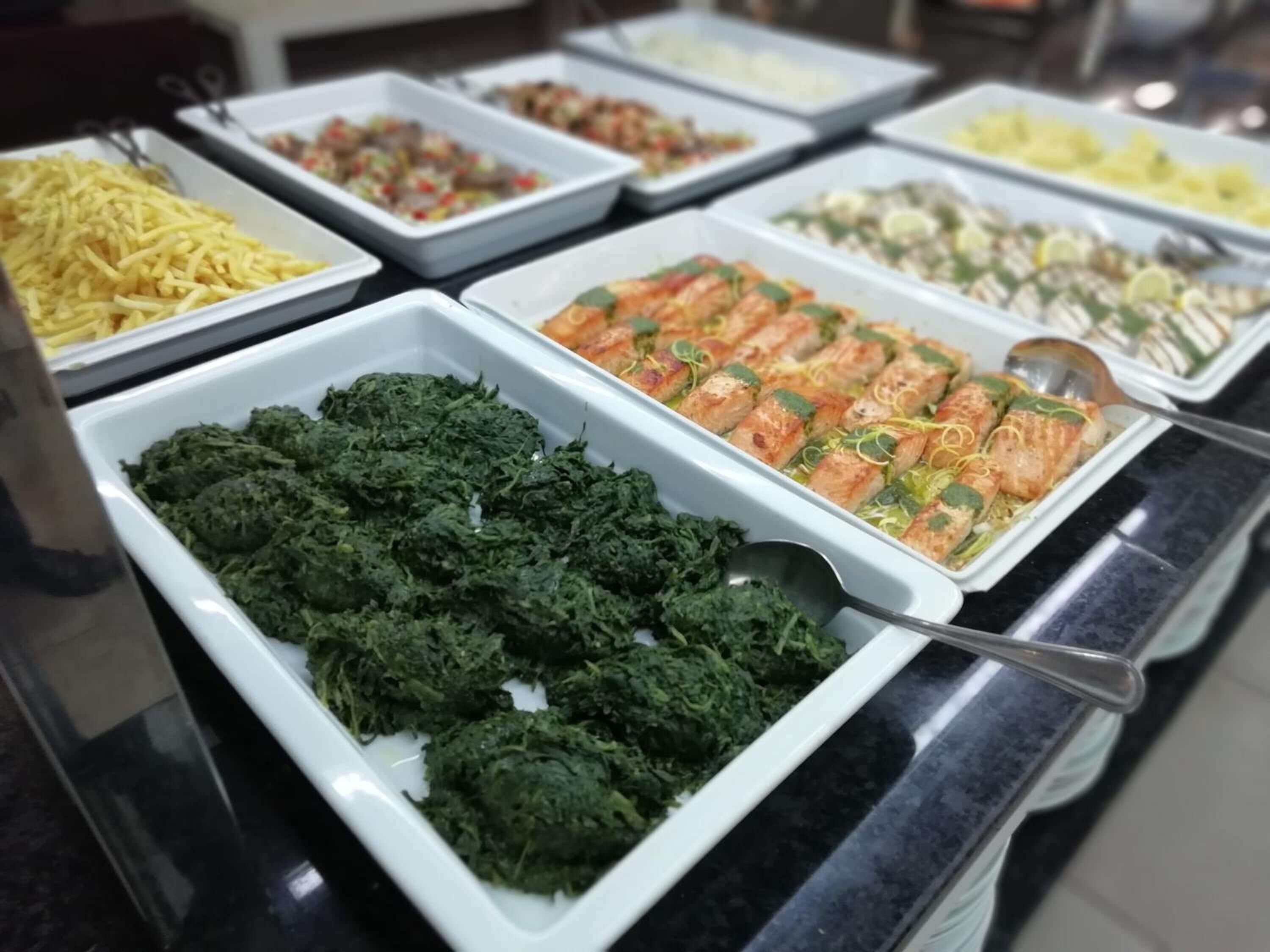 Un buffet proposant une variété de plats, dont un assortiment de légumes verts.