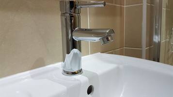 Un lavamanos de baño con grifo cromado y dispensador de jabón.