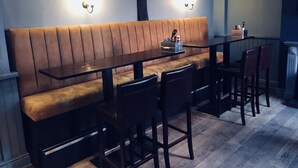 A restaurant with a wooden bench seating area, a long table, and bar stools. - The Old Post Office (Shrewsbury)