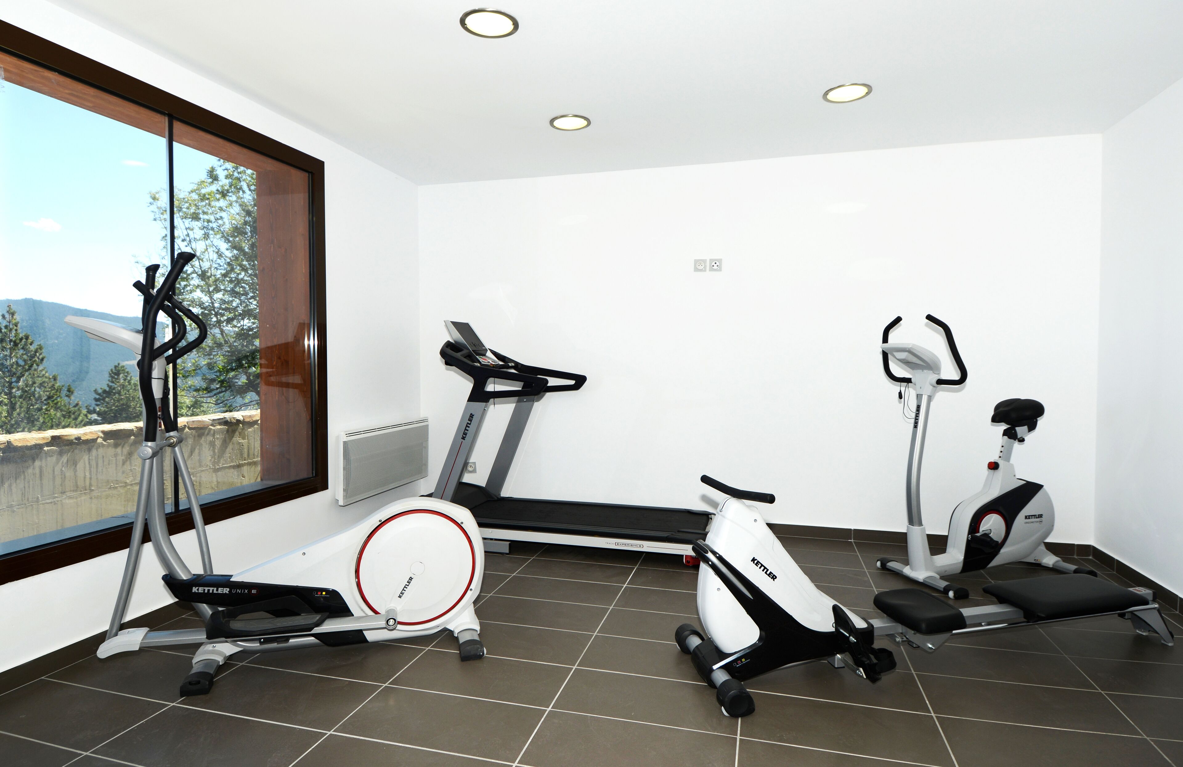 Un gimnasio moderno con tres bicicletas estáticas, una cinta de correr y una máquina de remo.