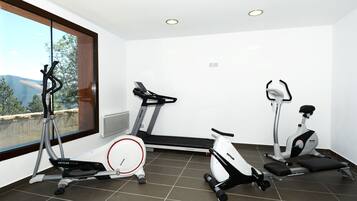 Un gimnasio moderno con tres bicicletas estáticas, una cinta de correr y una máquina de remo.