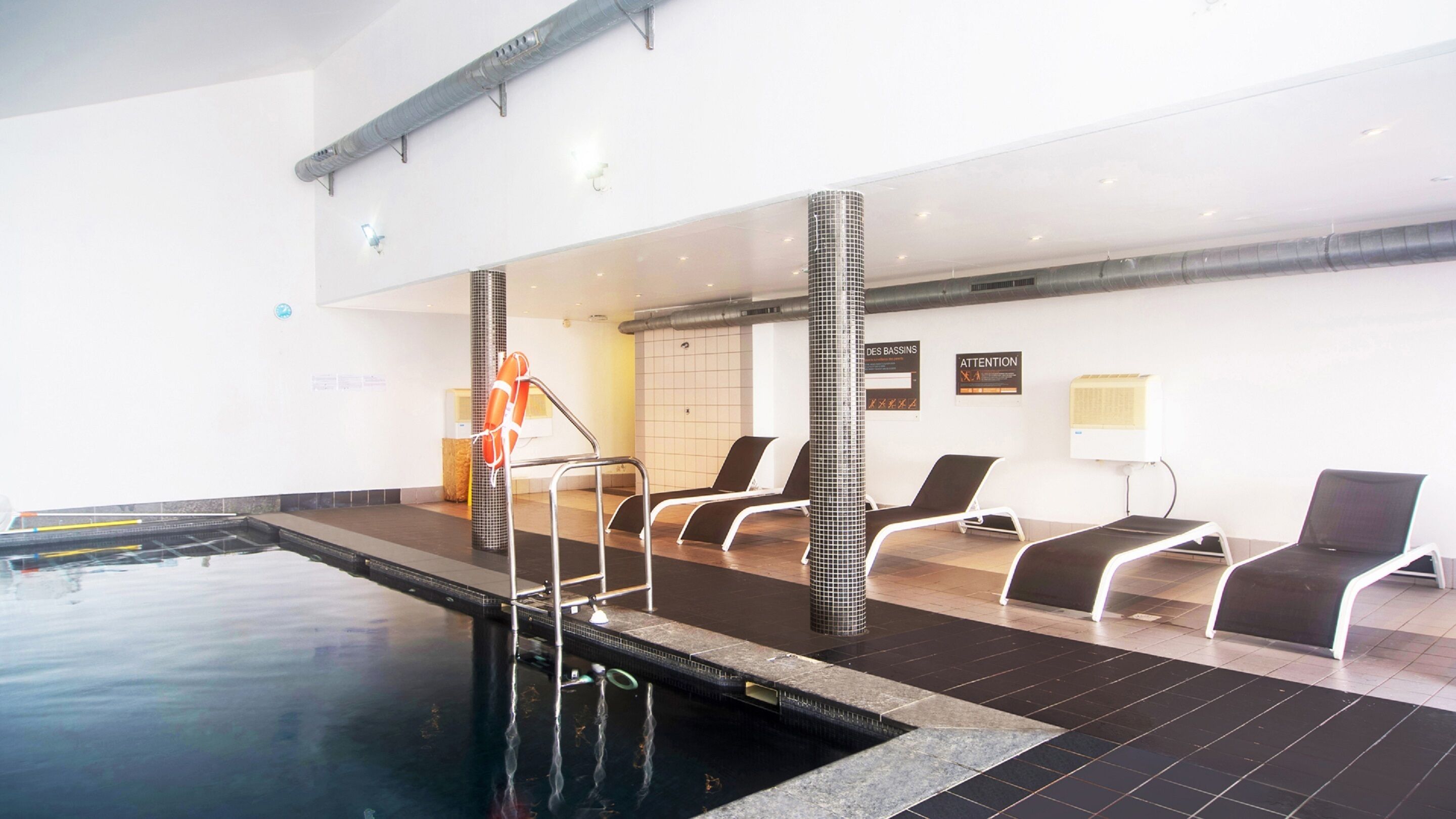 An indoor swimming pool with lounge chairs and a lifebuoy.