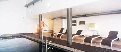 An indoor swimming pool with lounge chairs and a lifebuoy.