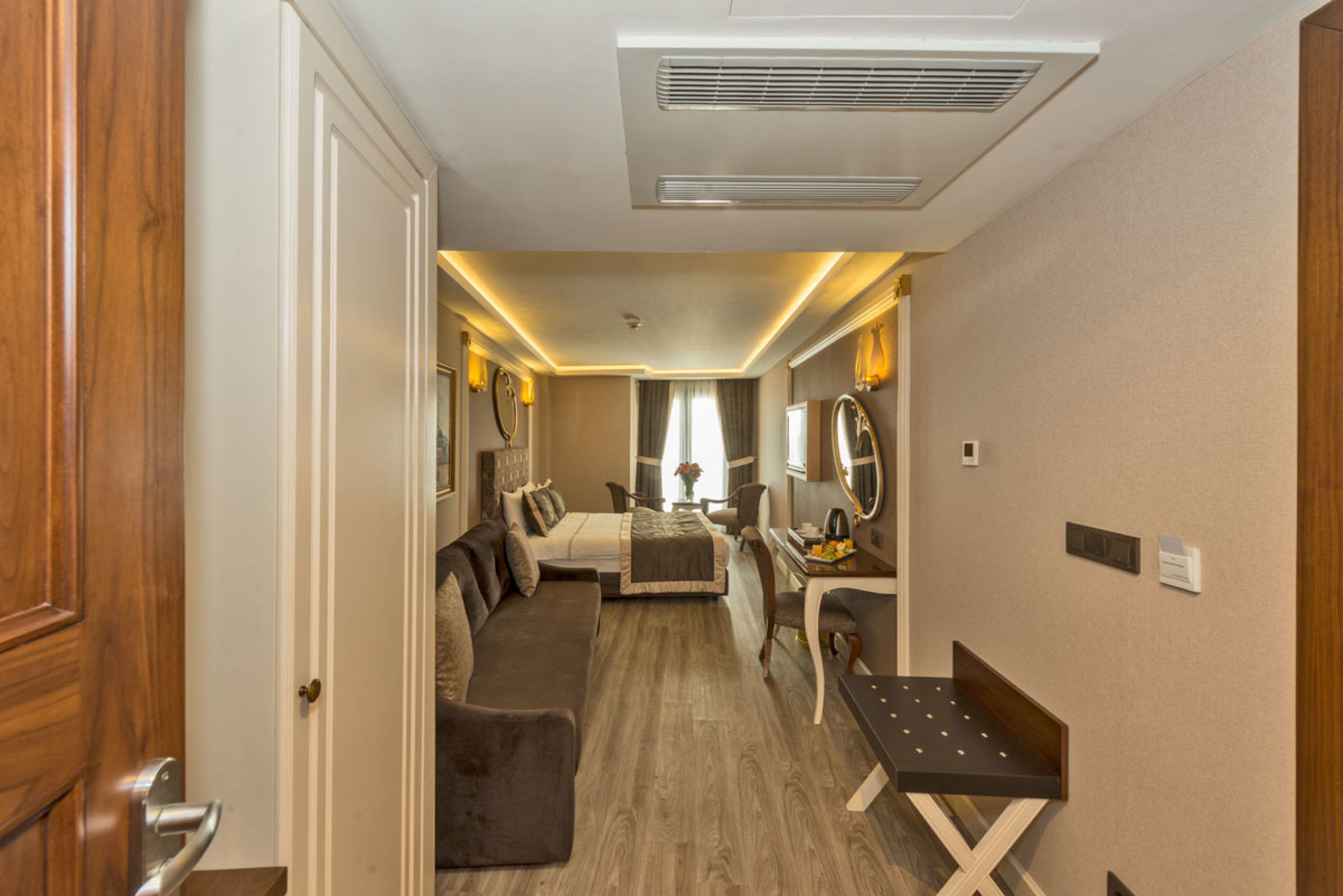 Un dormitorio compacto con cama, sofá, escritorio y espejo.