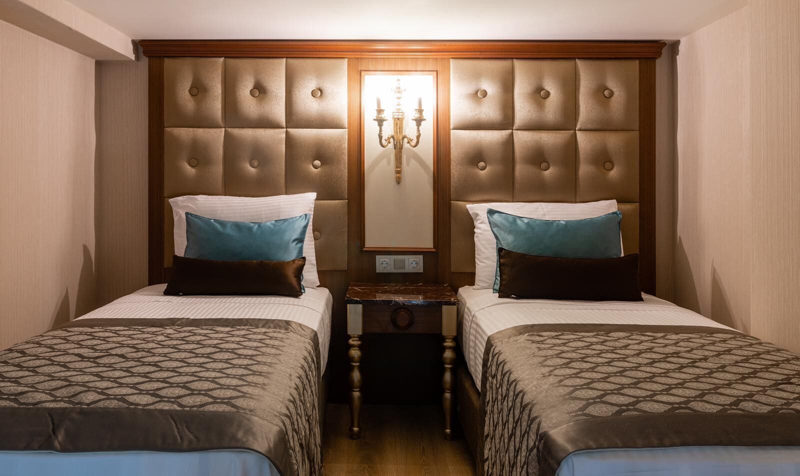 A hotel room with two beds, a wooden headboard, a nightstand, and a mirror.