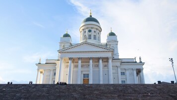 Un grande edificio bianco con una cupola centrale e due cupole più piccole ai lati, caratterizzato da elementi architettonici classici e statue.