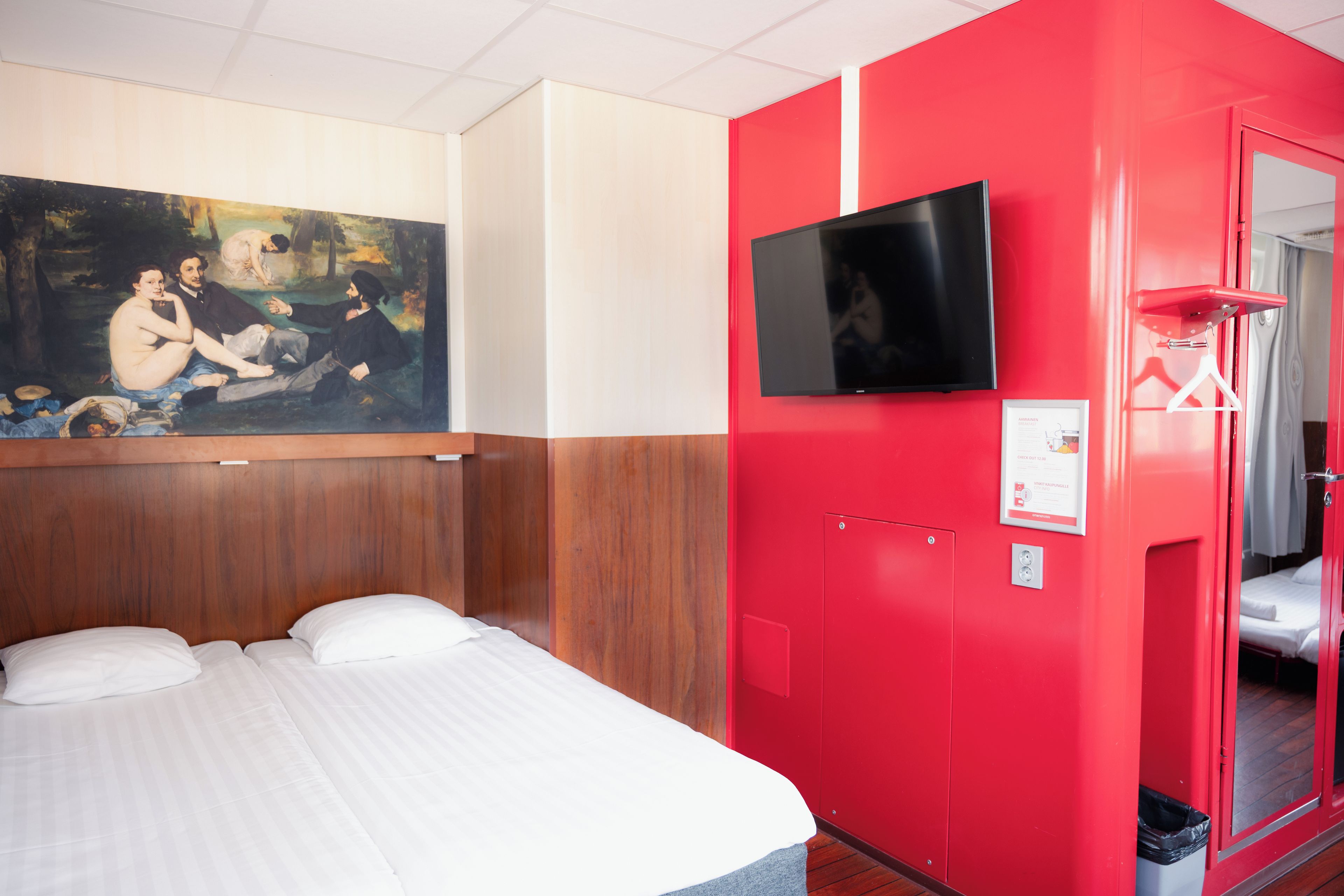 Een hotelkamer met een bed, een schilderij aan de muur, een televisie en een rode deur.