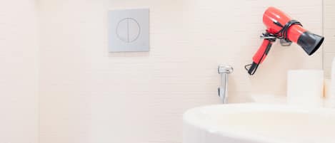 Une salle de bain équipée de toilettes, d’un lavabo, d’un porte-serviettes et d’un sèche-cheveux.
