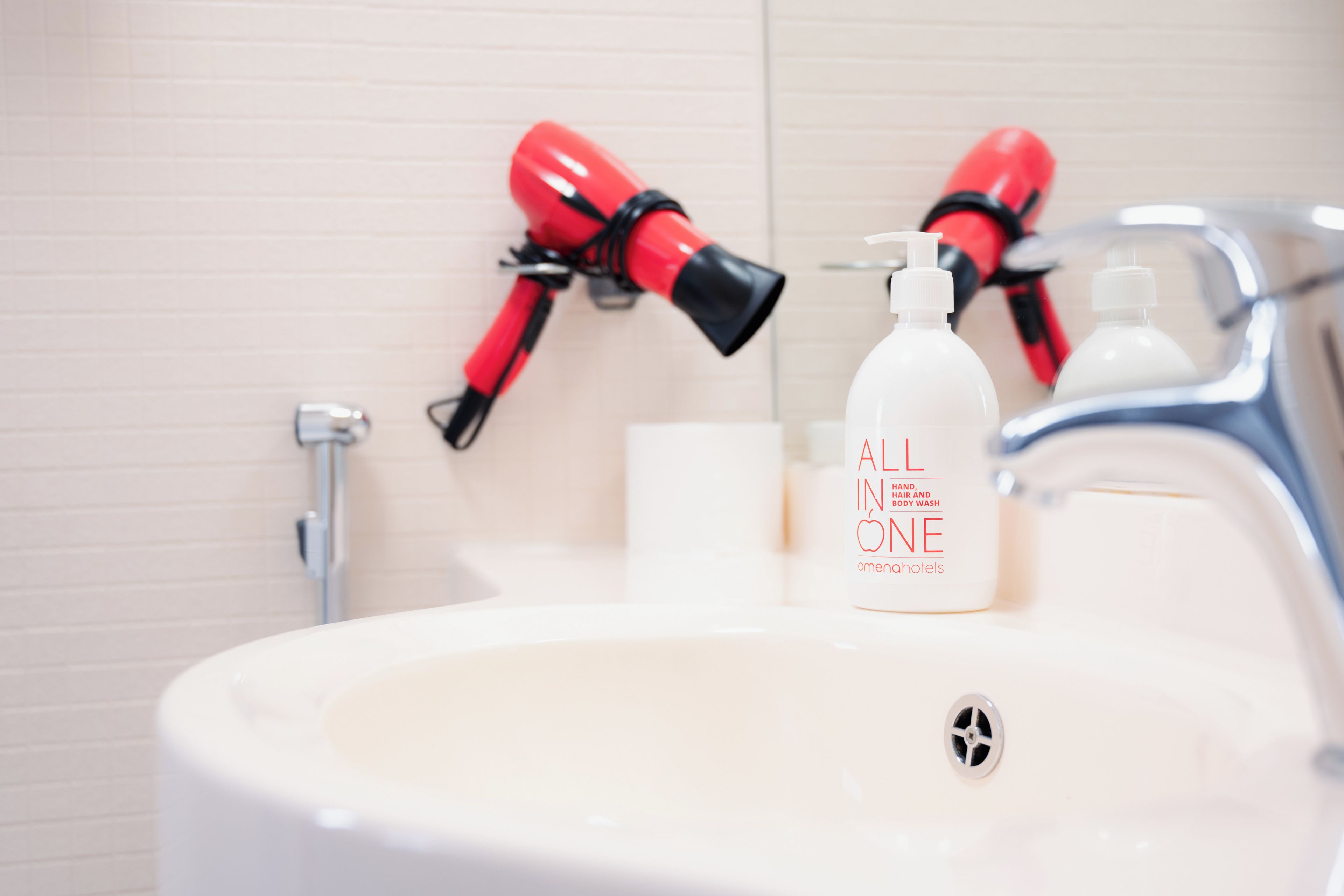 A bathroom sink with a bottle of hand, hair, and body wash.