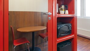 A compact kitchenette with a microwave, a small fridge, and a shelf with kitchen essentials. - Omena Hotel Helsinki City Center (Helsinki)