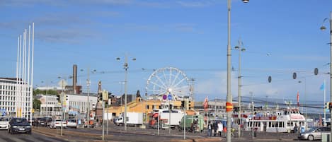 A waterfront area with a Ferris wheel, street lamps, and a variety of buildings including a hotel with a sign that reads "SIGHTSEEING".