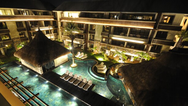 A rooftop pool area with lounge chairs, a thatched-roof structure, and a water feature. - Domaine des Alizées by Fine and Country (Grand-Baie)
