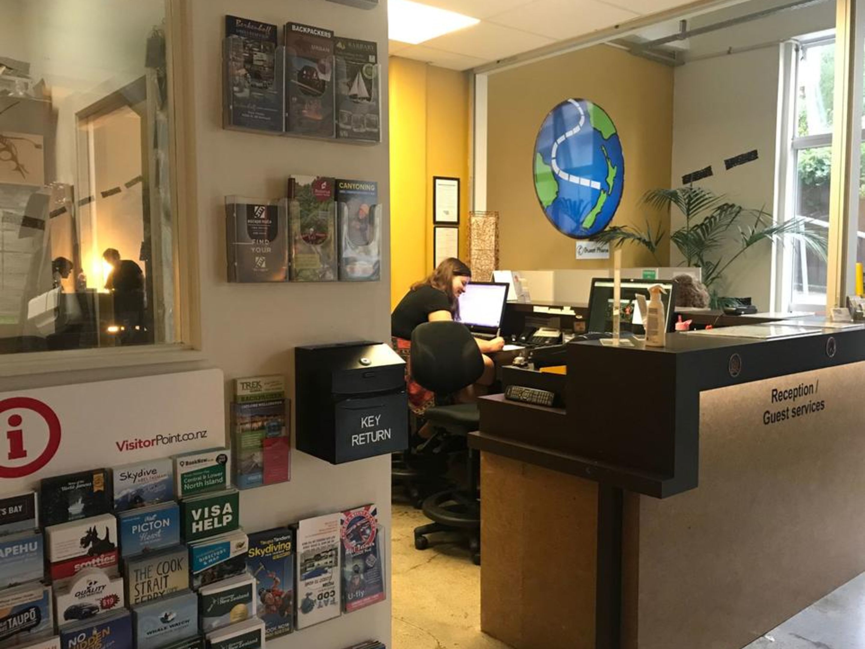 Una recepción con un adorno de globo terráqueo, una computadora y un buzón para devolución de llaves.