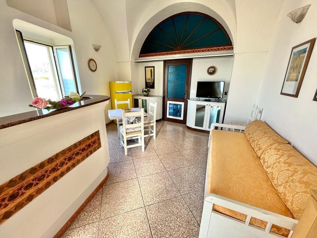Een knus woongedeelte met een kitchenette, een bank, een eethoek en een kleine televisie.