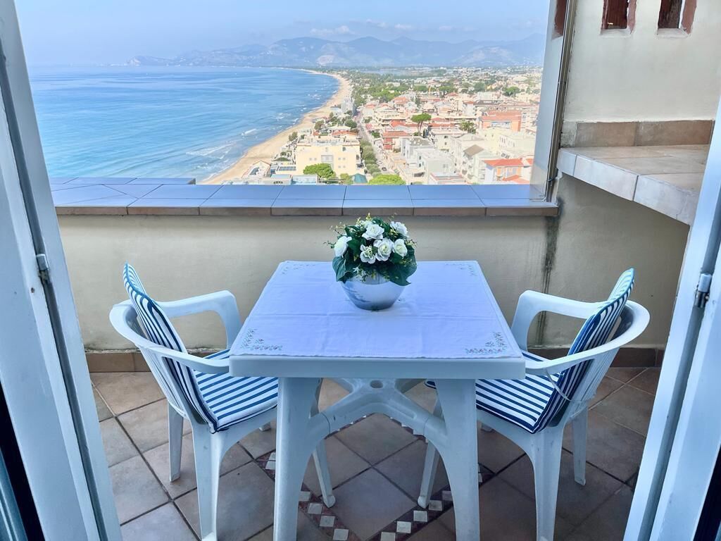 Un balcó amb taula i cadires, amb vista a una platja i al skyline de la ciutat.